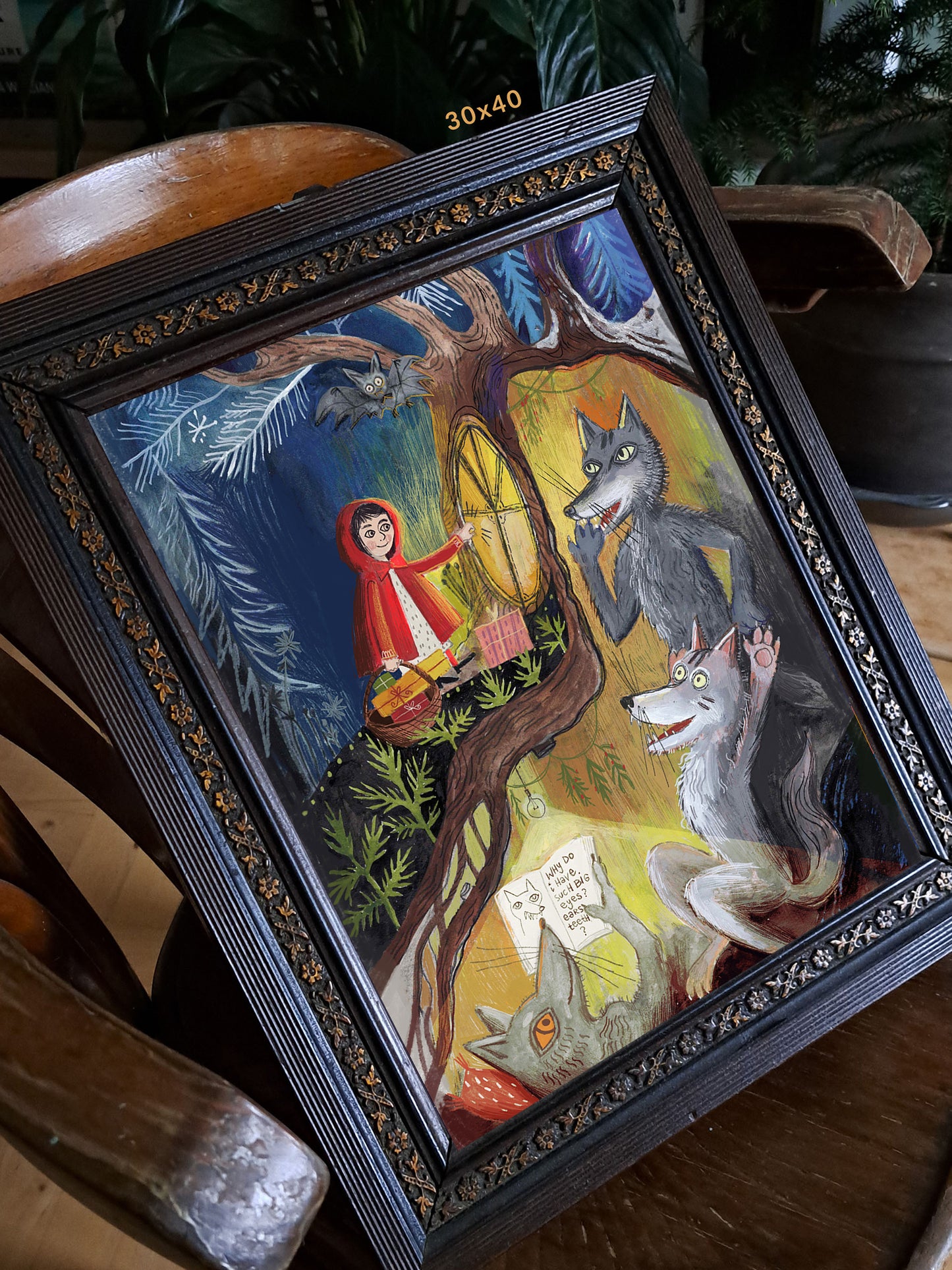 Wydruk „Czerwony Kapturek – prawdziwa historia" w ciemnej zdobionej ramie 30x40 cm na drewnianym krześle – baśniowa ilustracja z wilczą rodziną i Czerwonym Kapturkiem, Natalia Noszczyńska