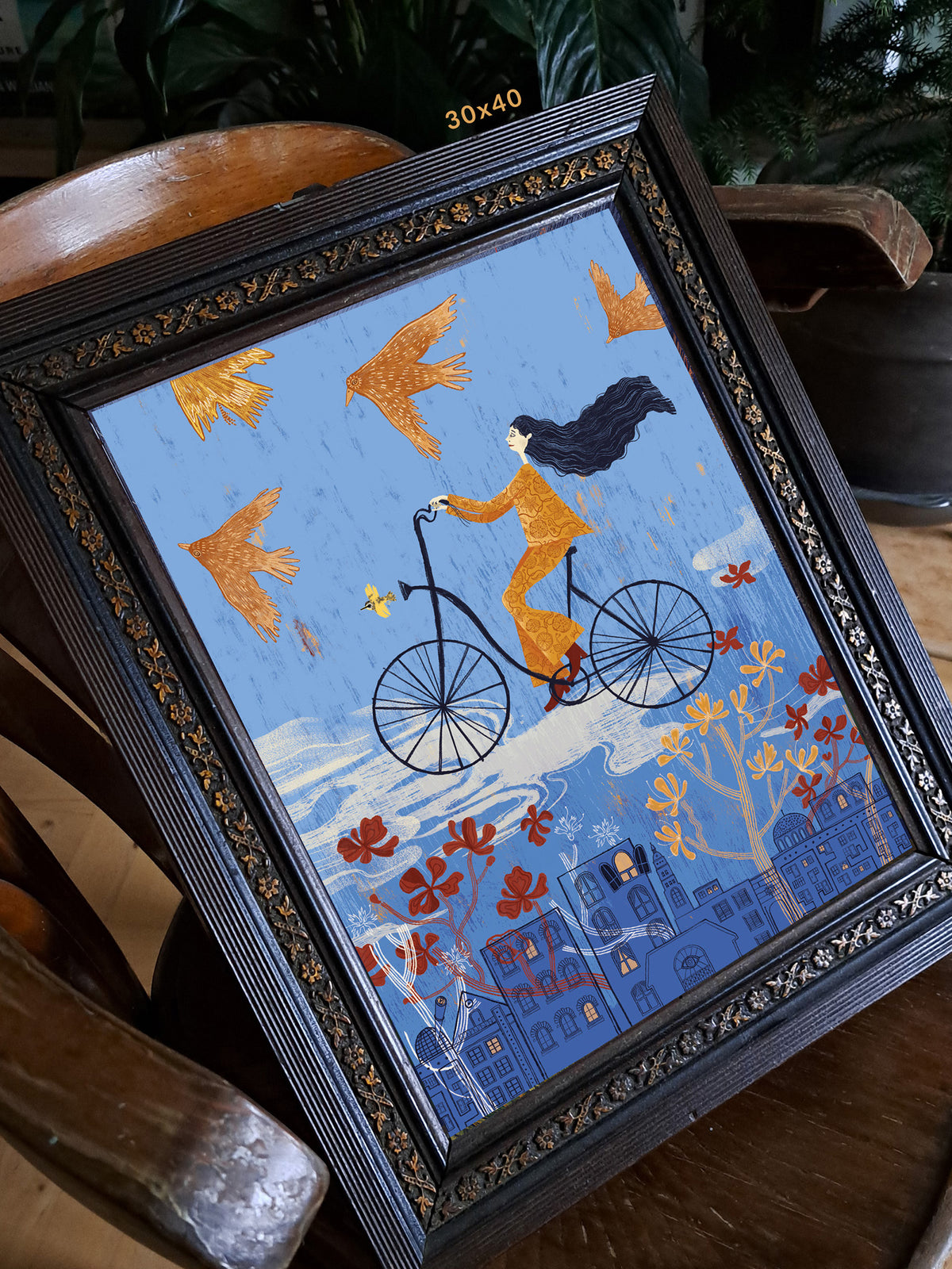 Wydruk „Bujanie w obłokach” w ozdobnej ciemnej ramie na drewnianym fotelu, aranżacja formatu 30 × 40 cm.