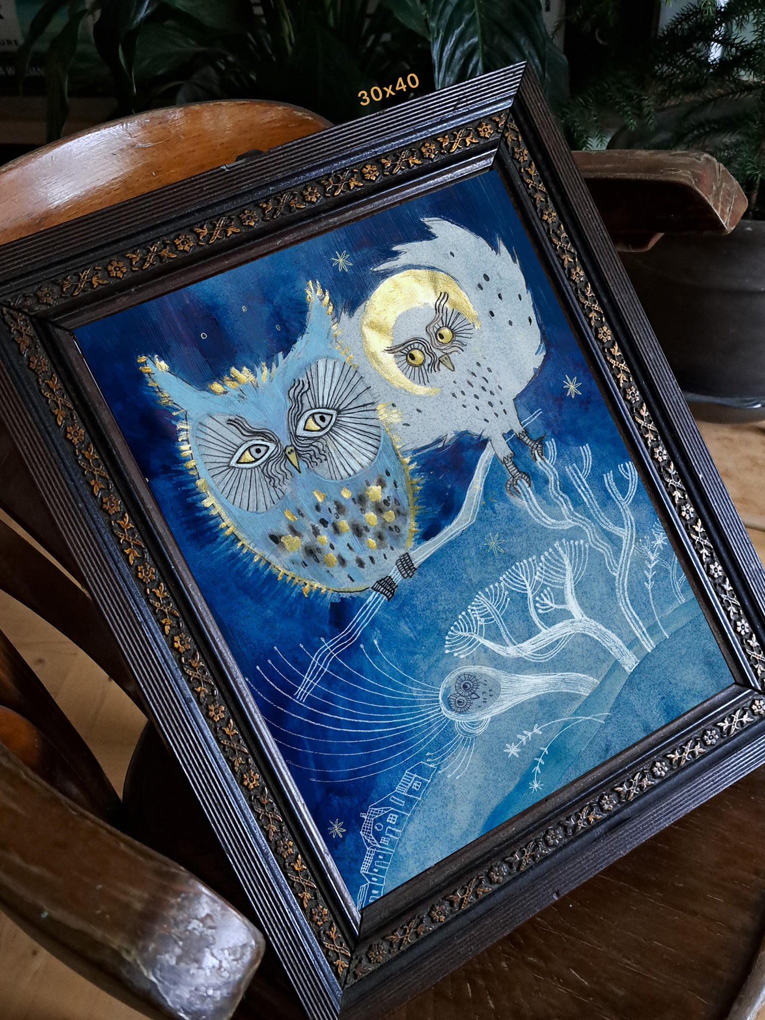 Wydruk „Sowa na gaju siada i gada" w ciemnej zdobionej ramie 30x40 cm na drewnianym krześle – nocna ilustracja z sowami w stylu folklorystycznym